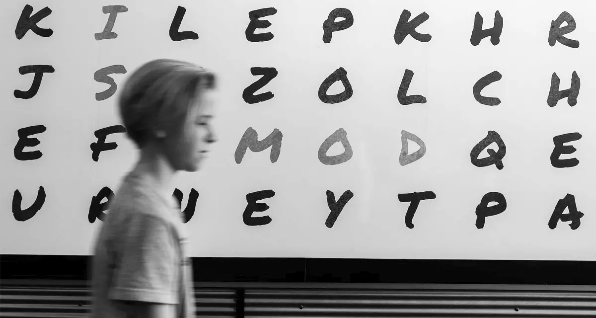 Mensch lÃ¤uft an Wand mit Buchstaben vorbei. Symbolfoto Analphabetismus. Foto: unsplash.com | John Jennings.