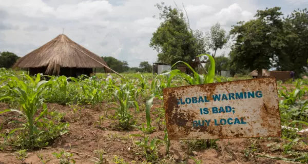 Schild mit der Aufschrift â€žGlobal warming is bad, buy localâ€œ als UnterstÃ¼tzung fÃ¼r sÃ¼dsudanesische FlÃ¼chtlinge in Uganda. Foto: Â© UNHCR/Jordi Matas