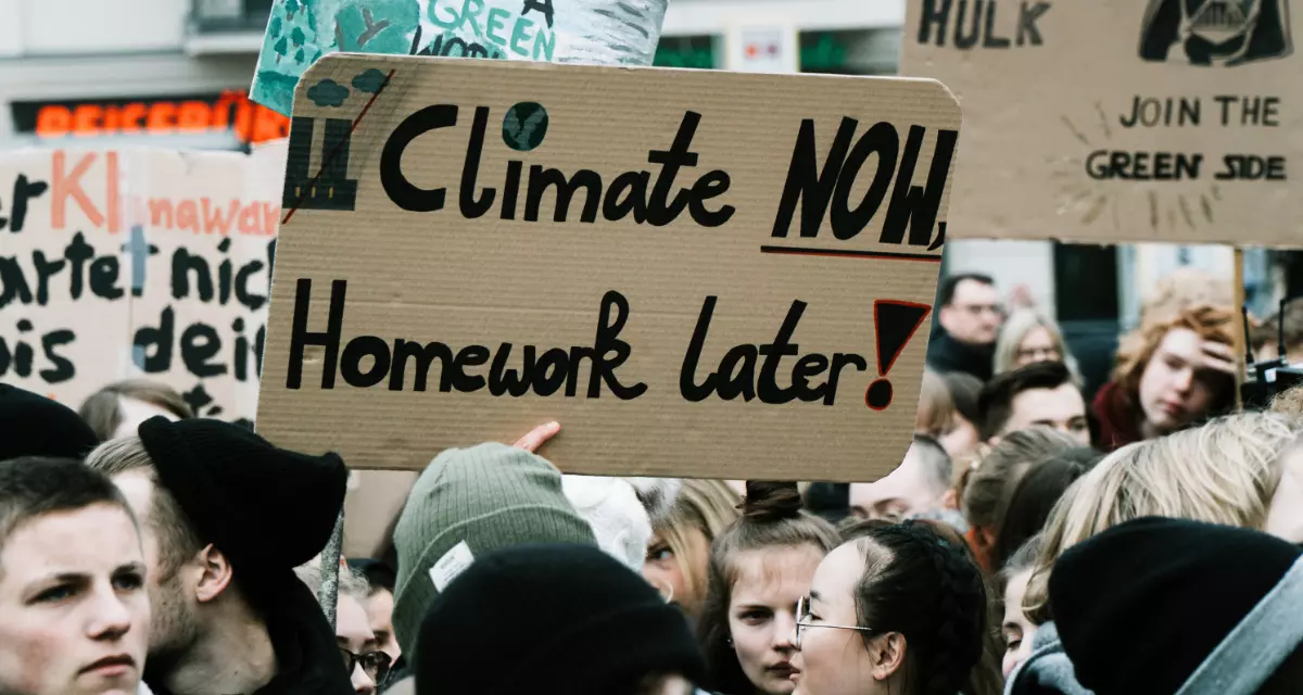 SchÃ¼ler bei einer Demonstration gegen Klimawandel halten Plakat mit dem Schriftzug "Climate now, Homework later" (Ãœbersetzung: Klima jetzt, Hausaufgaben spÃ¤ter) hoch.