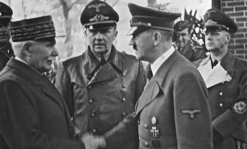 Philippe PÃ©tain schÃ¼ttelt Adolf Hitler die Hand. Zwischen beiden steht Dolmetscher Paul Schmidt, rechts ReichsauÃŸenminister Joachim von Ribbentrop.