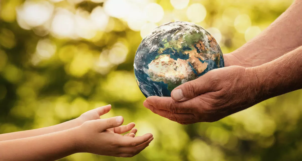 HÃ¤nde eines Ã¤lteren Menschen reichen eine Weltkugel an KinderhÃ¤nde.