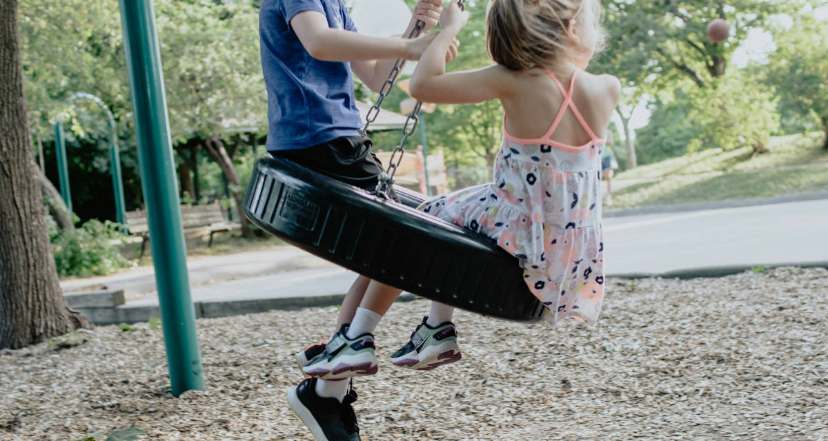 Spielende Kinder Kinder auf einer Reifenschaukel