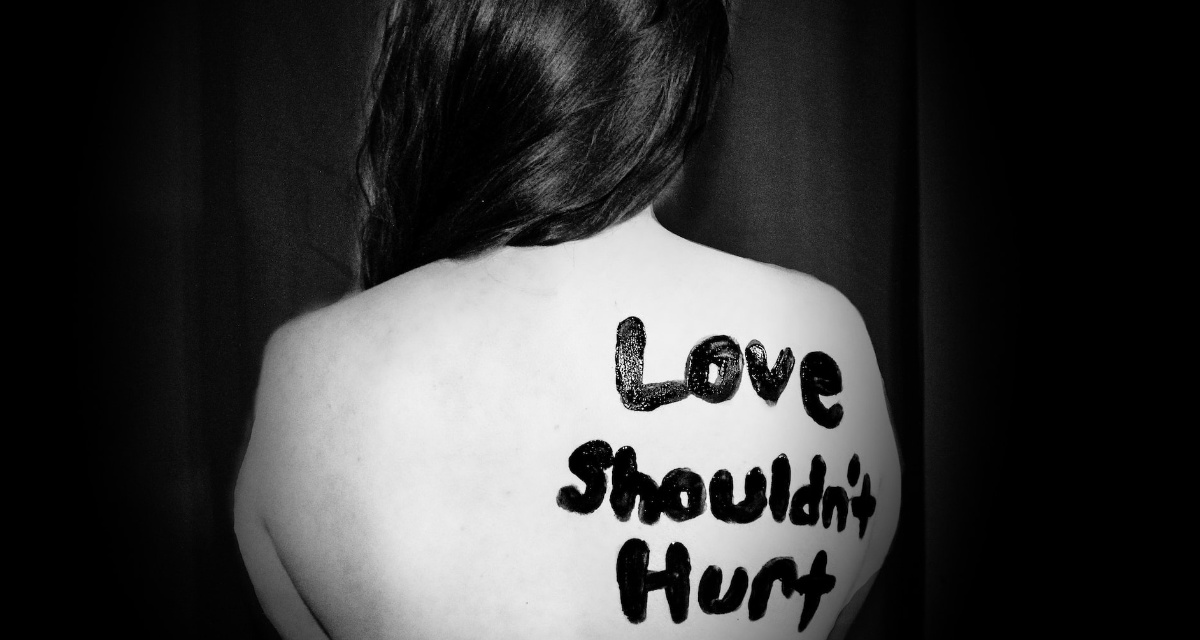 Frau mit dem Schriftzug â€žLove shouldn't hurtâ€œ auf dem RÃ¼cken. Foto: unsplash.com | Sydney Sims
